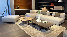 The Freifrau Mia sofa in beige fabric can be arranged in many different ways with a recamier and pouf, and is now available at a reduced price in the design sale at Grünbeck Einrichtungen.